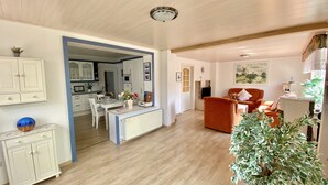 A spacious living area with a dining table, a sofa, and a large potted plant. - Vacation apartment, ground floor, WLAN, covered terrace, wood-burning stove (Krummhörn)