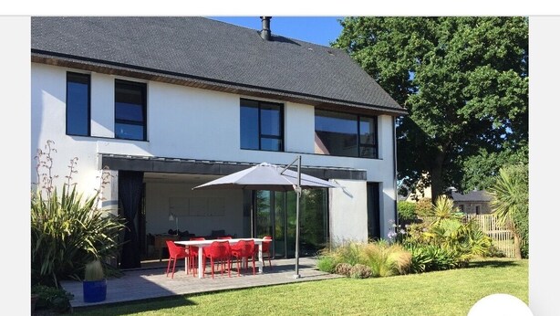A modern two-story house with a covered patio area, a dining table with chairs, and a large umbrella. - House on the edge of the Gulf of Morbihan, the beach 2 minutes walk. (Baden)
