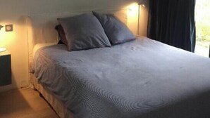 A bedroom with a bed, bedside lamps, and a hanging light fixture. - House on the edge of the Gulf of Morbihan, the beach 2 minutes walk. (Baden)