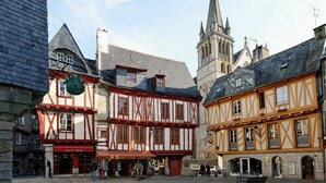 A cobblestone square with traditional half-timbered buildings, a church spire, and a bench. - House on the edge of the Gulf of Morbihan, the beach 2 minutes walk. (Baden)