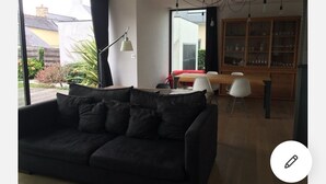 A modern living room with a black sofa, a dining table with chairs, and a wooden cabinet. - House on the edge of the Gulf of Morbihan, the beach 2 minutes walk. (Baden)