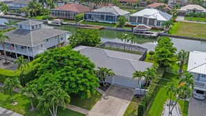A residential area with houses, a large tree, and a water body. - Waterfront Piece of Paradise at Tiger Tail (Marco Island)