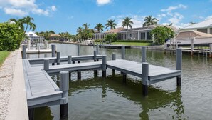 A marina with docks extending into calm water, surrounded by palm trees and residential buildings. - Waterfront Piece of Paradise at Tiger Tail (Marco Island)