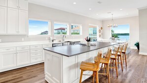 A spacious kitchen with a large island, white cabinetry, and a view of a lake. - Waterfront | Private Pool | Pet-Friendly | Boat Slip (Gulf Shores)