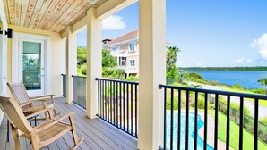A wooden deck with two rocking chairs, a pool, and a view of a residential area and water. - Waterfront | Private Pool | Pet-Friendly | Boat Slip (Gulf Shores)