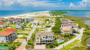 A coastal residential area with beachfront properties, including houses with balconies, a swimming pool, and a well-maintained landscape. - Waterfront | Private Pool | Pet-Friendly | Boat Slip (Gulf Shores)