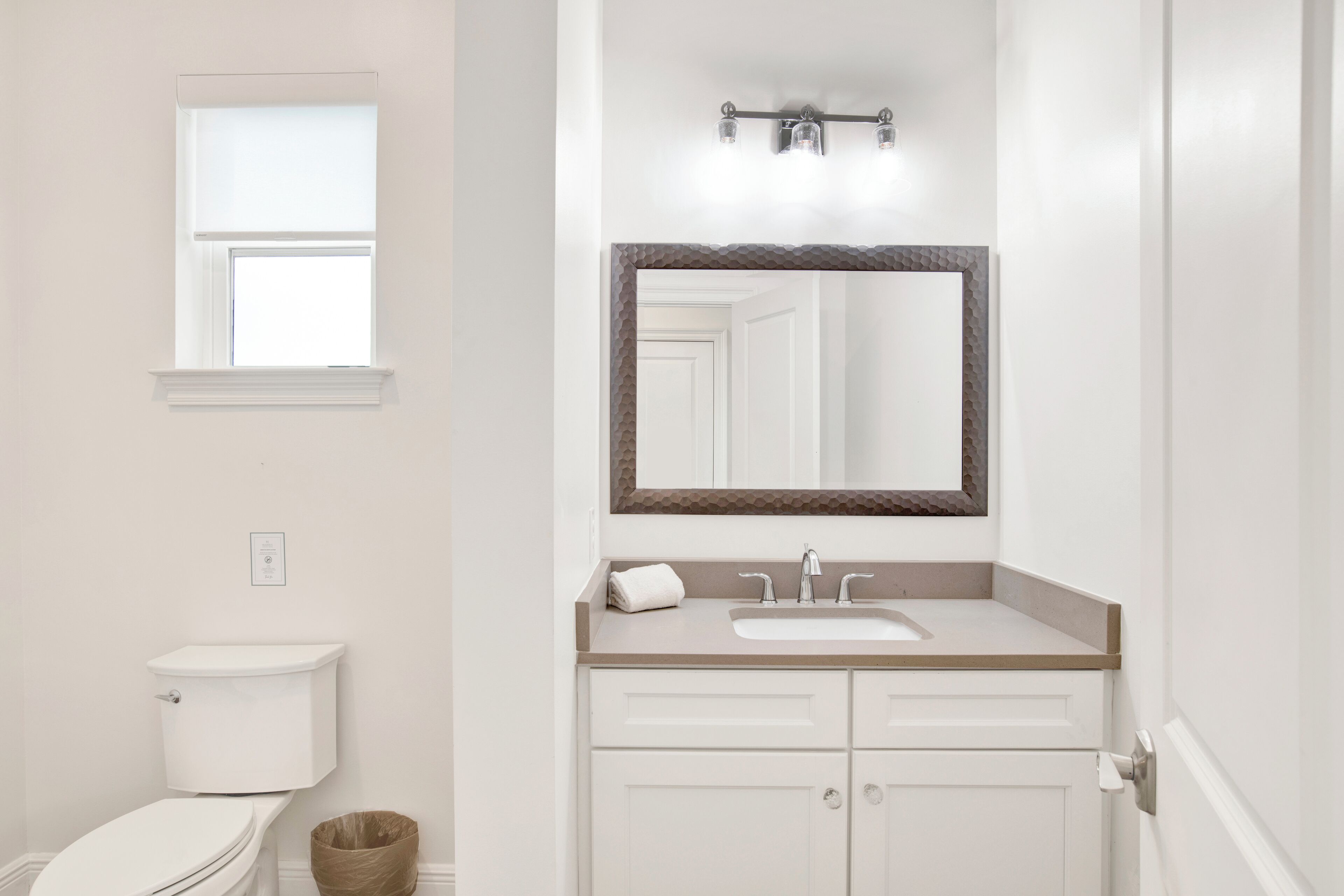 A bathroom with a toilet, sink, and mirror.