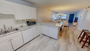 A modern kitchen with white cabinets, a granite countertop, and a built-in microwave.