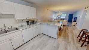 A modern kitchen with white cabinets, a granite countertop, and a built-in microwave.