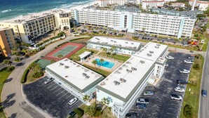 An aerial view of a hotel with multiple buildings, a swimming pool, and a parking lot.