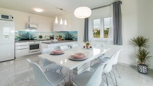 Una cocina moderna con armarios blancos, una isla central e iluminación colgante.