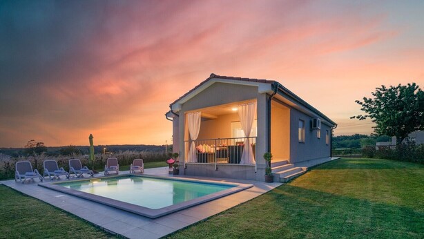 Una casa moderna con piscina y zona de estar exterior.