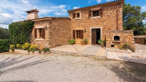 Una casa in pietra con tetto in tegole, un camino e un piccolo giardino con piante in vaso.