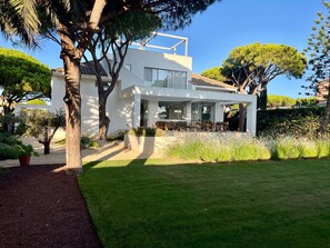 A modern two-story house with a patio and a well-maintained garden.