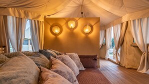 A cozy bedroom with a large bed, three wall-mounted lights, and a wooden floor. - Terme di Vulci Glamping & SPA (Canino)
