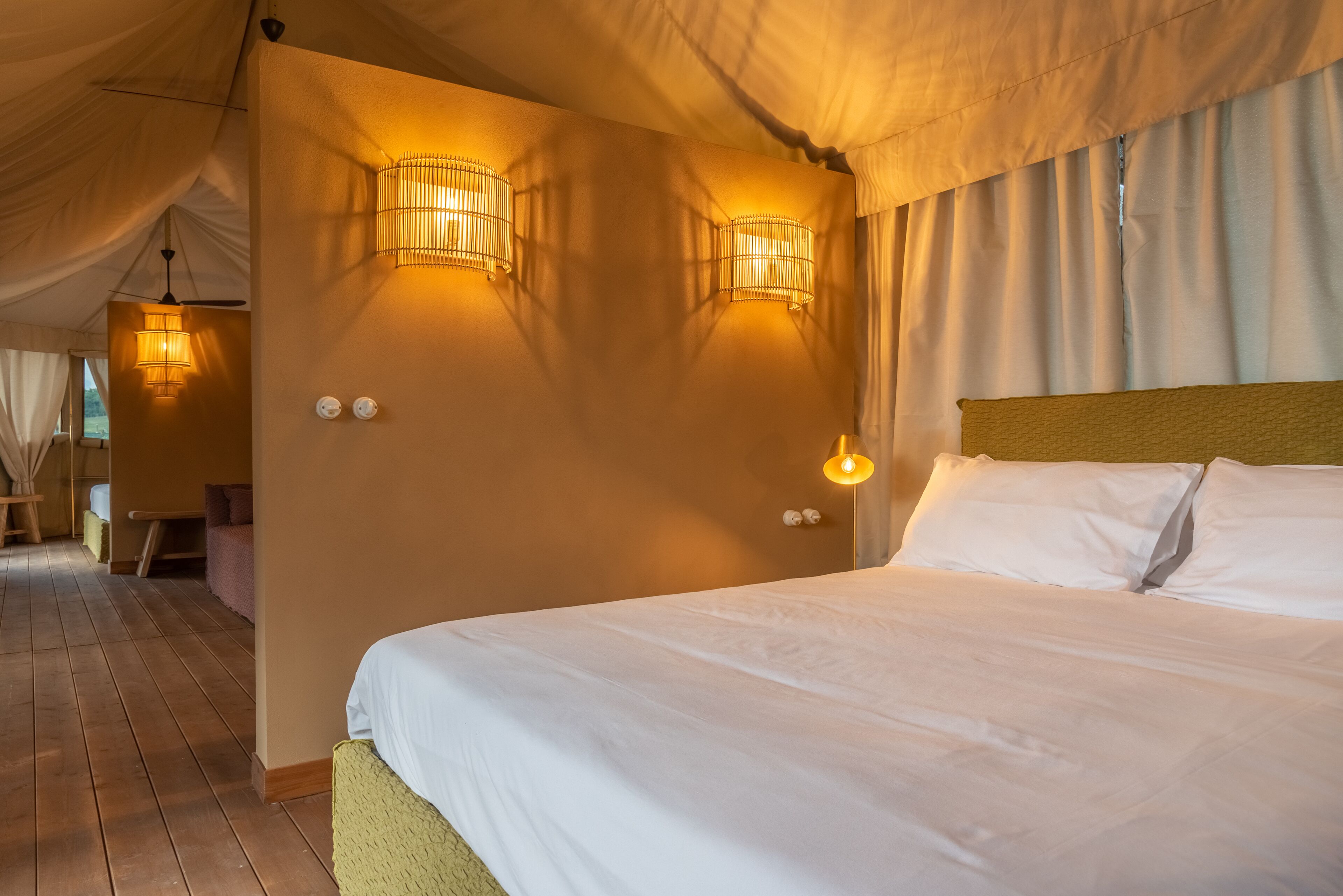 A bedroom with a large bed, two wall-mounted lamps, and a ceiling fan.