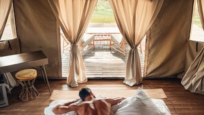 A tent-style room with a bed, a desk, and curtains. - Terme di Vulci Glamping & SPA (Canino)
