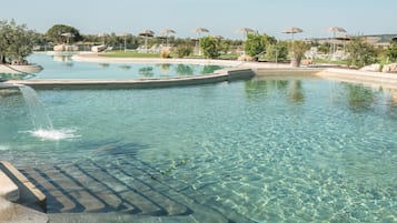 Una piscina al aire libre de temporada, sombrillas