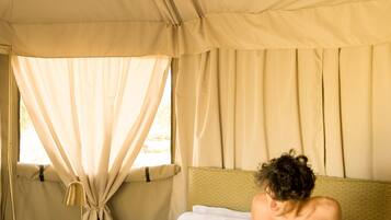 Una carpa con una cama, un ventilador de techo y una lámpara.
