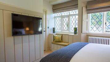 A bedroom with a bed, a television mounted on the wall, a window with a view, and a radiator.