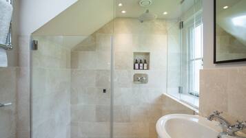 Ein modernes Badezimmer mit einer gläsernen Duschkabine, einer großen Badewanne und einem Fenster mit Tageslicht.