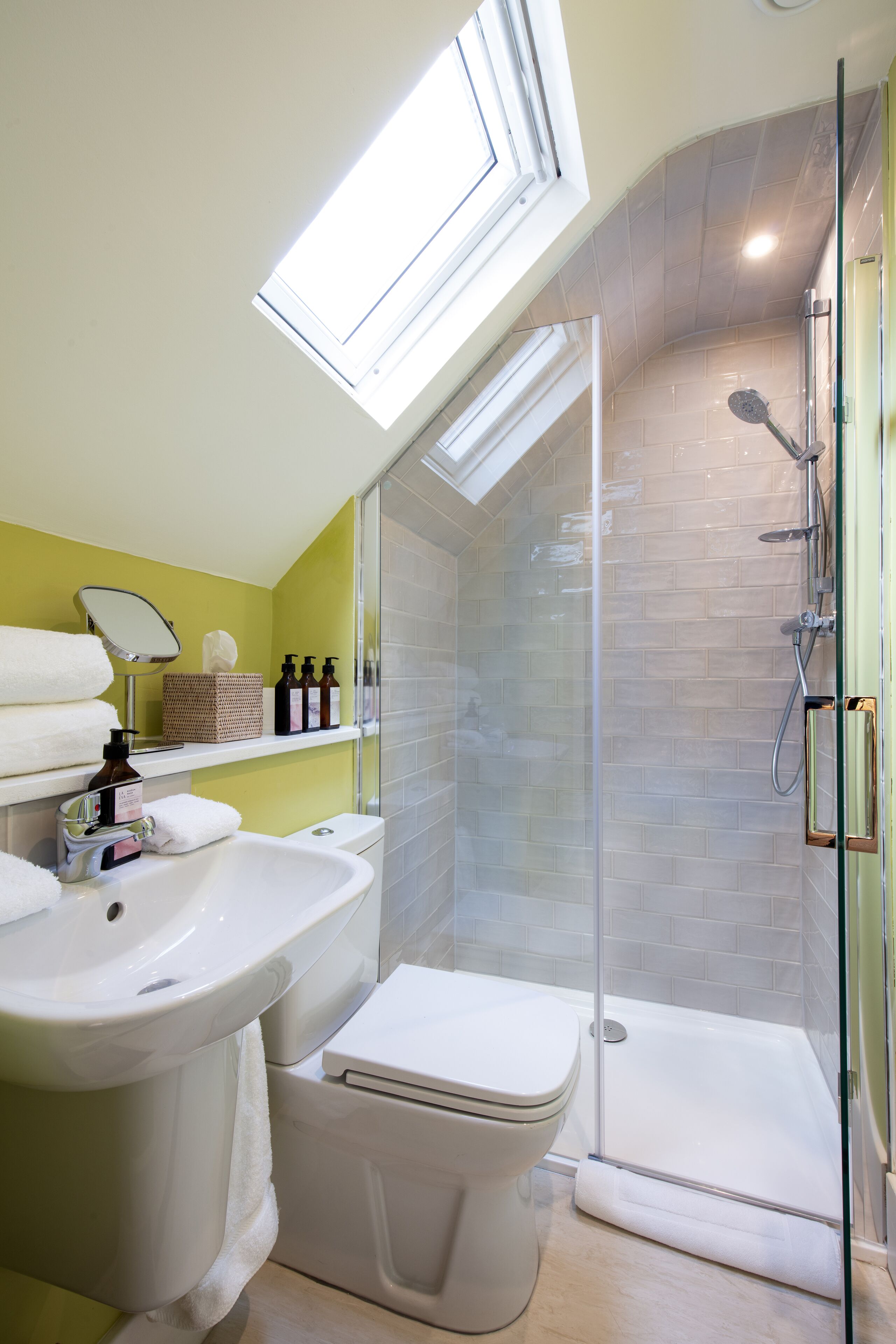 Ein modernes Badezimmer mit Oberlicht, Duschkabine, Toilette und Waschbecken.