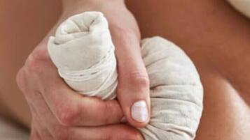 A close-up of a person's hands applying a white compress to another person's arm.