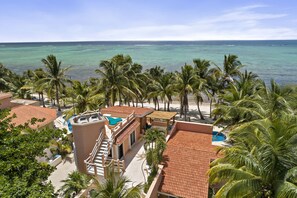 Een resort met een zwembad, palmbomen en uitzicht op de oceaan.