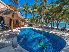 A swimming pool with a curved edge, surrounded by palm trees and a beach view. - Casa Rosa Crystal Sand Exquisite Beach & Pool  Minutes from Tulum (Tulum)