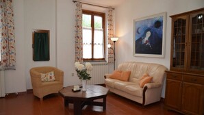 Ein Wohnzimmer mit einem Korbsessel, einem Ledersofa, einem Couchtisch und einem Schrank.