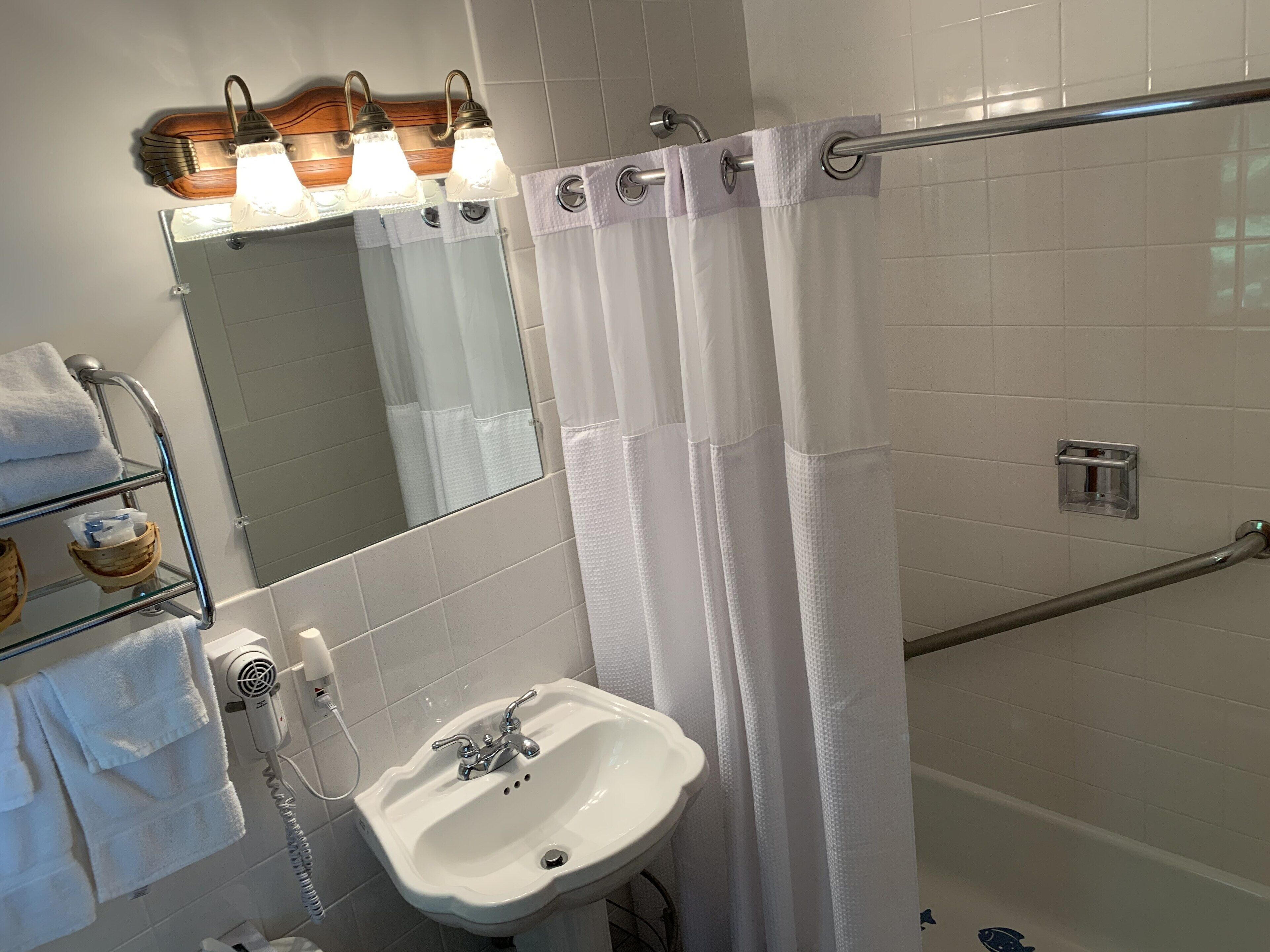 A bathroom with a white sink, a mirror, a towel rack, and a shower curtain.