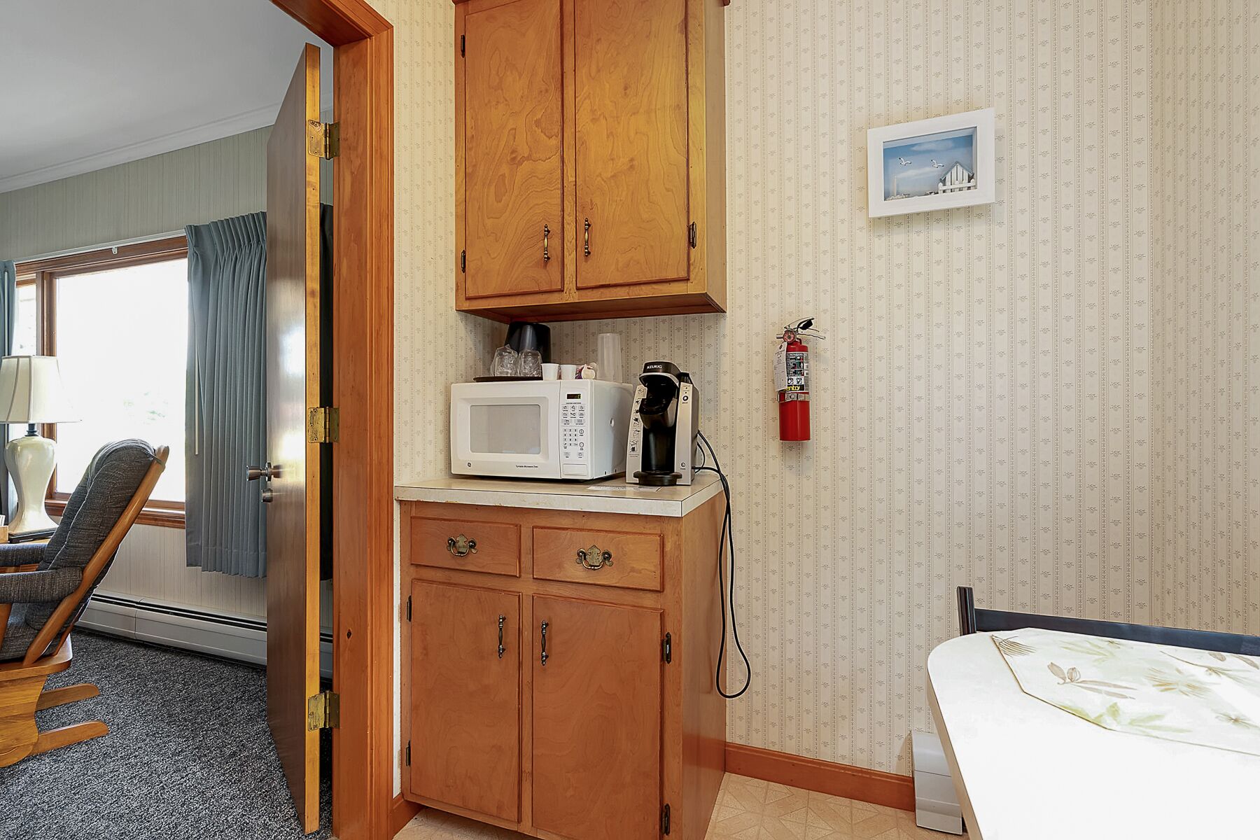 A small kitchenette with a microwave, coffee maker, and a fire extinguisher on the wall.