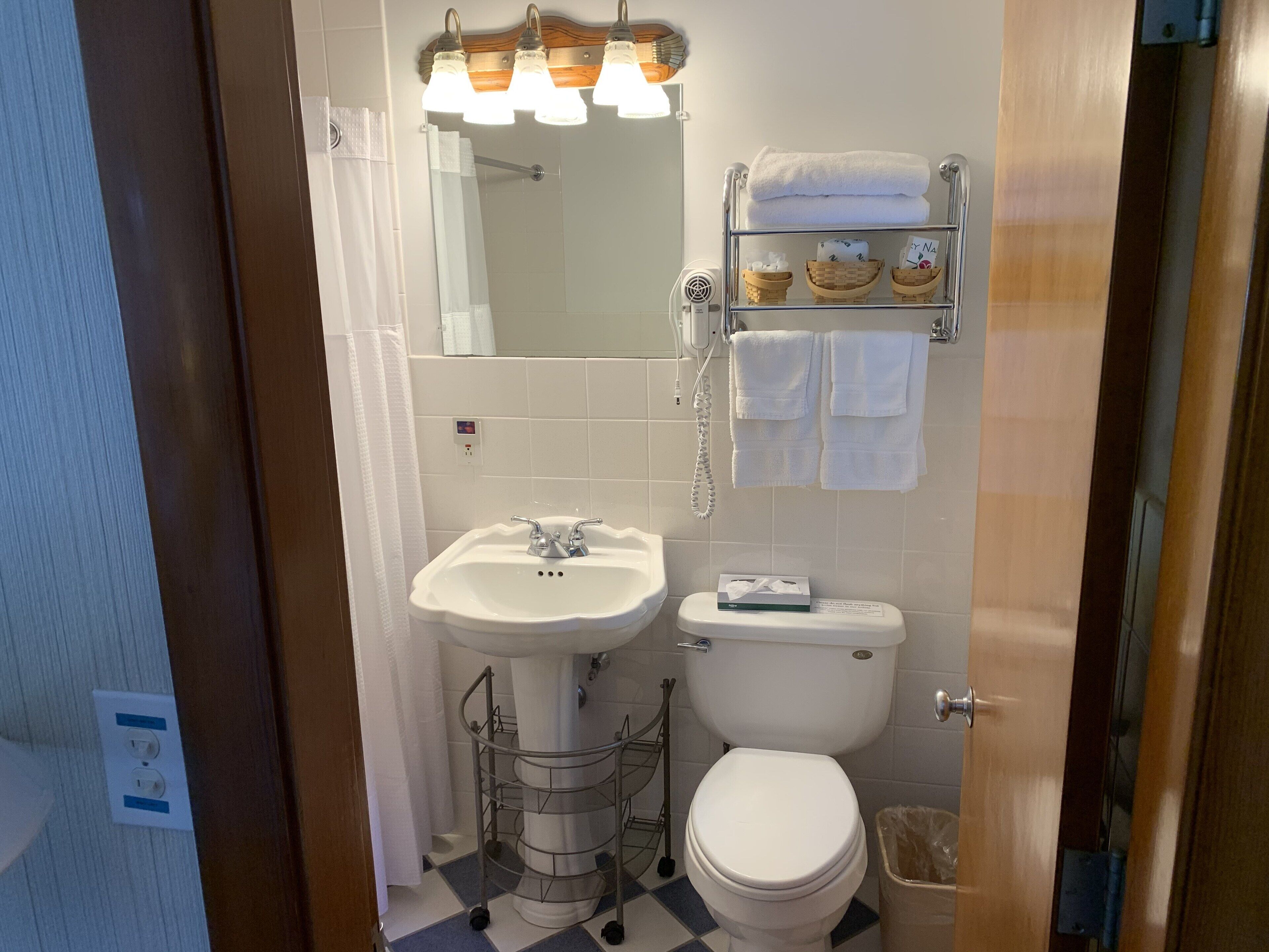 Un baño con lavamanos, inodoro y un perchero con varias toallas.