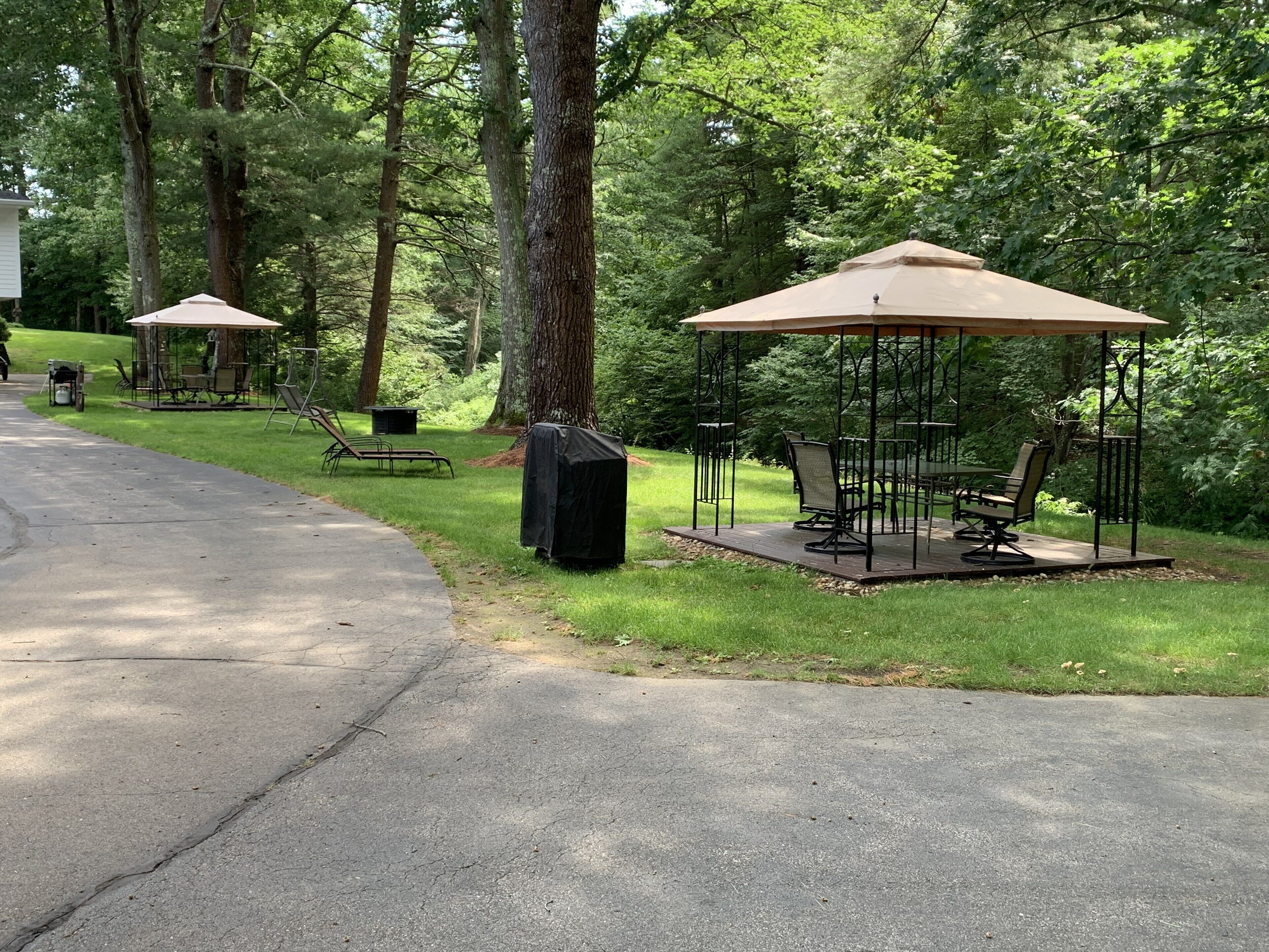 A gazebo with a table and chairs, surrounded by trees.