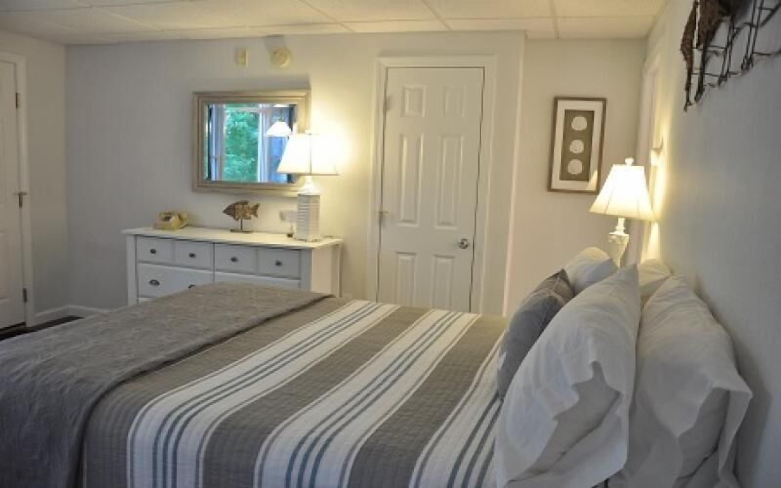 A bedroom with a bed, dresser, and two bedside lamps.