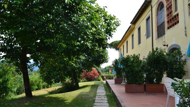 A garden pathway leading to a building with a yellow facade and arched windows. - Appartamento Ilaria (San Macario in Monte/Lucca)