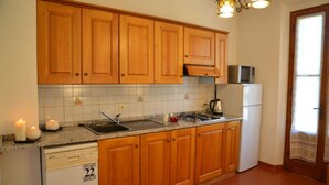 A kitchen with wooden cabinets, a sink, a stove, a microwave, and a dishwasher. - Appartamento Ilaria (San Macario in Monte/Lucca)