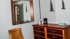 A room with a wooden dresser, a mirror, and decorative pine tree wall decals. - The Gold Pan Motel (Eagle Nest)