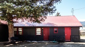 A building with a red roof and a black facade, featuring two red doors and a small window. - The Gold Pan Motel (Eagle Nest)