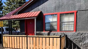 A building with a red door and windows, a wooden fence, and a sign that says "SLOW DOWN PEDESTRIANS." - The Gold Pan Motel (Eagle Nest)