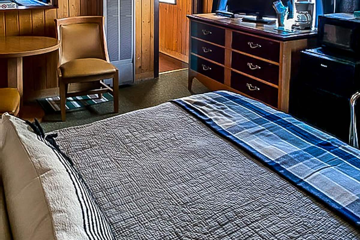 Une chambre comprenant un lit, un bureau, une chaise, une commode, un téléviseur et un ventilateur de plafond.