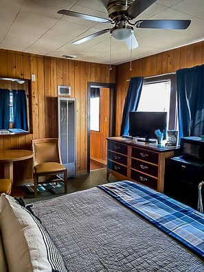A room with a bed, a desk, a chair, a dresser, a television, and a ceiling fan. - The Gold Pan Motel (Eagle Nest)
