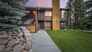 A modern two-story building with a stone retaining wall, a concrete pathway, and a well-maintained lawn. - Family Mountain Oasis: Pools, Hot Tubs & Summer Fun! (Park City)