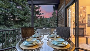 An outdoor dining area with a table set for four, surrounded by chairs, overlooking a forested landscape. - Family Mountain Oasis: Pools, Hot Tubs & Summer Fun! (Park City)