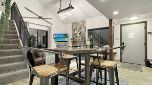 Eine moderne Küche mit Essbereich, einer Treppe und einem an der Wand befestigten Fernseher.