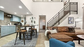 A modern kitchen with a dining area, a staircase, and a living room with a sofa and coffee table. - Family Mountain Oasis: Pools, Hot Tubs & Summer Fun! (Park City)