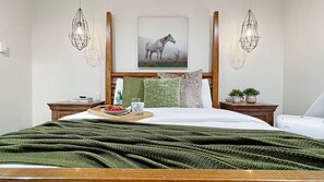 A neatly made bed with a green blanket, a wooden headboard, and a framed picture of a horse on the wall.