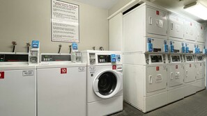 A laundry facility with multiple washing machines and dryers, each with a control panel and a numbered door.