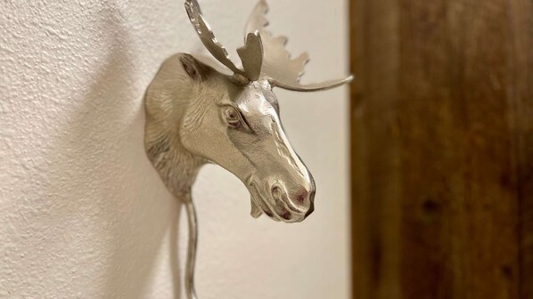 A mounted animal head, possibly a moose, against a textured wall.
