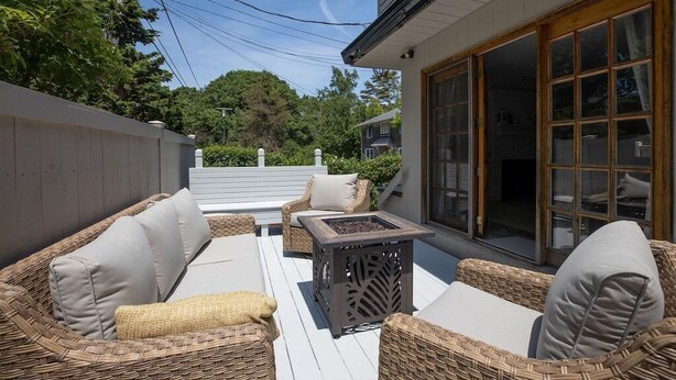Une terrasse extérieure aménagée avec des meubles en osier, une petite table et une porte vitrée donnant sur un espace abrité.